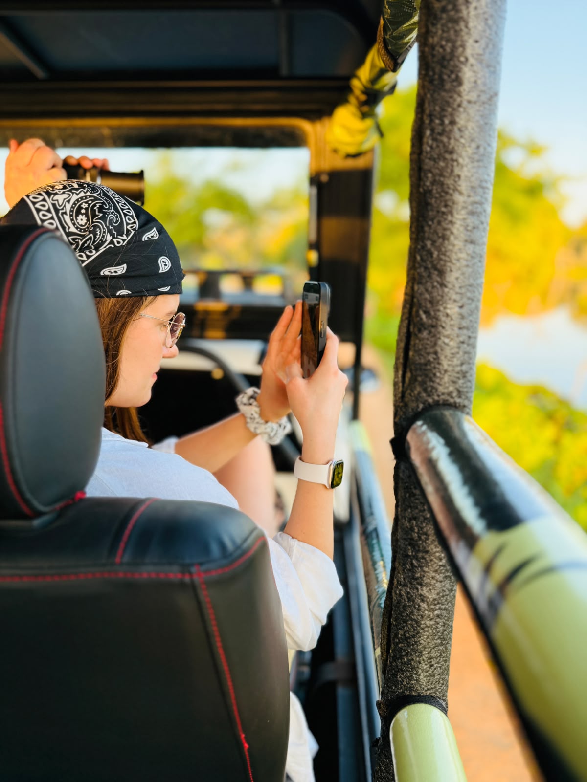 Traveler photographing wildlife from a safari jeep